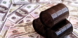 oil barrels miniature on top of dollar bills