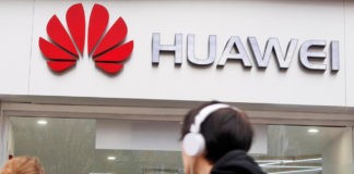 Wibest-Huawei: A man appears to look at the logo of Huawei.