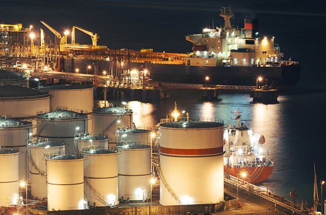 Wibest – Oil: An aerial shot of oil inventories and a ship behind on nighttime.