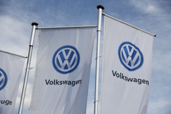 Flags with VW logo against blue sky.