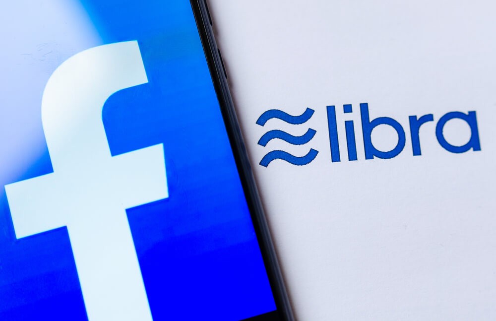 Wibest – Facebook Libra: Photo of the Facebook logo on the smartphone screen and the brochure with Libra logo.