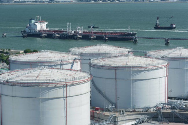Wibest – Oil Prices: An aerial shot of crude oil storages with oil tanker ships on the background.