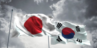 Japan & South Korea Flags are waving in the sky with dark clouds.