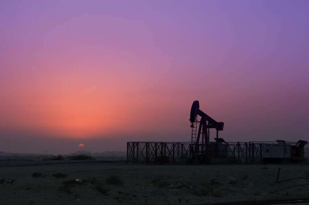 Wibest – Oil Prices: Crude oil pump jack over a purple sunset.