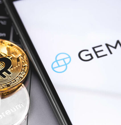 Digital Coins: Gemini logo on the screen smartphone with bitcoin on side.