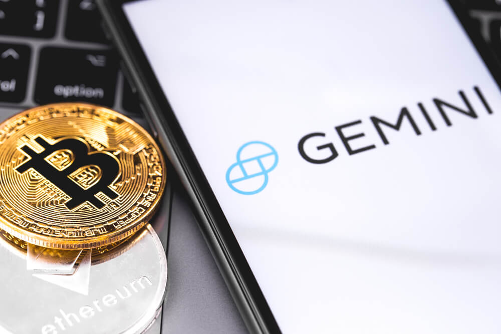 Digital Coins: Gemini logo on the screen smartphone with bitcoin on side.