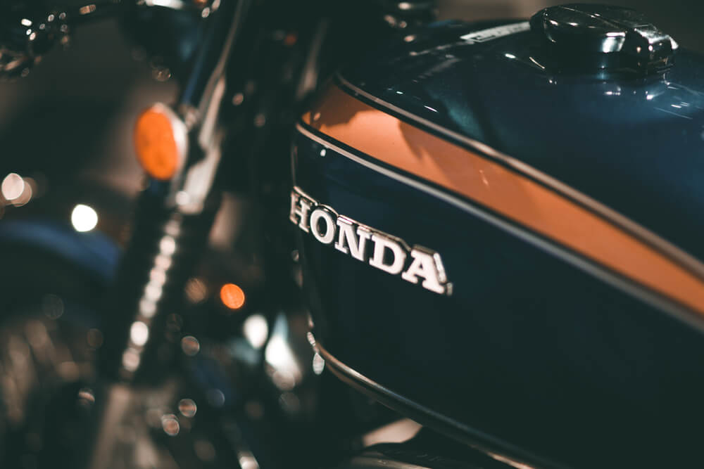 Honda Motorcycles: Tank of a Honda blue motorcycle with yellow stripes, focusing on the Honda logo.