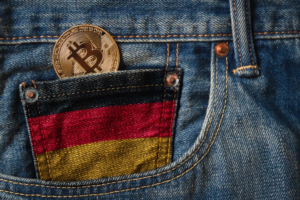 German: Golden BITCOIN (BTC) cryptocurrency in the pocket of jeans with the flag of Germany