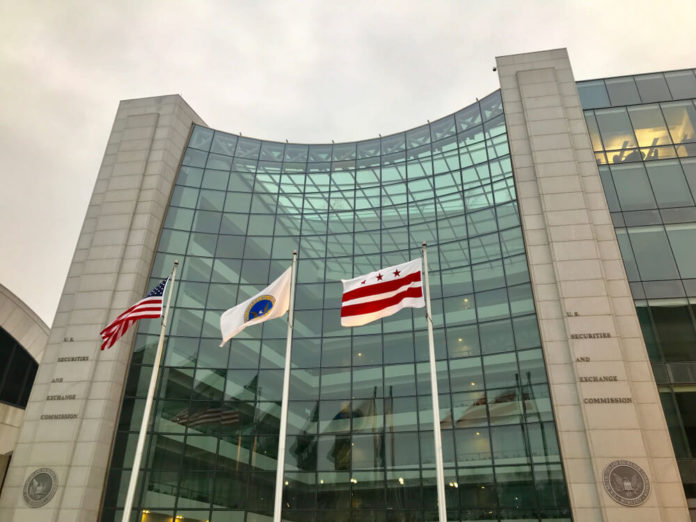 SEC: SEC sign at entrance to DC headquarters building with flags.