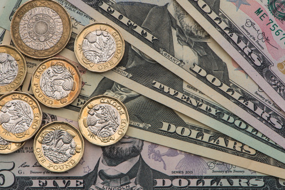 Wibest – GBP/USD: British pound sterling coins over US dollar bills.