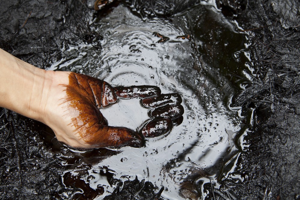 Wibest – Petroleum and Oil: Crude oil spilled a hand touching its surface.