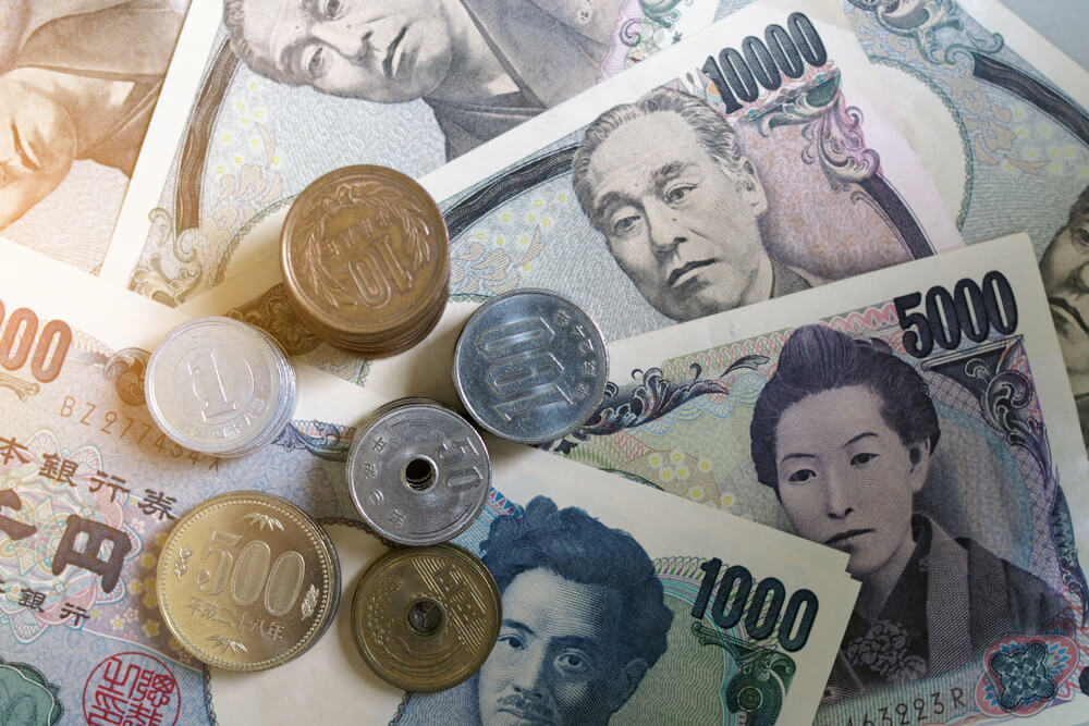 Wibest – Monetary Policy: Japanese yen bills over a trading chart. 