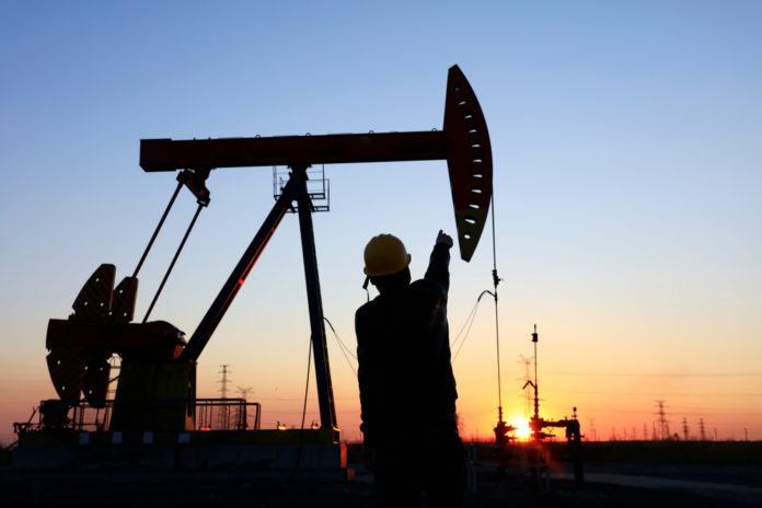 Wibest – Oil and Petroleum: A worker and an oil pump jack over the sunset.