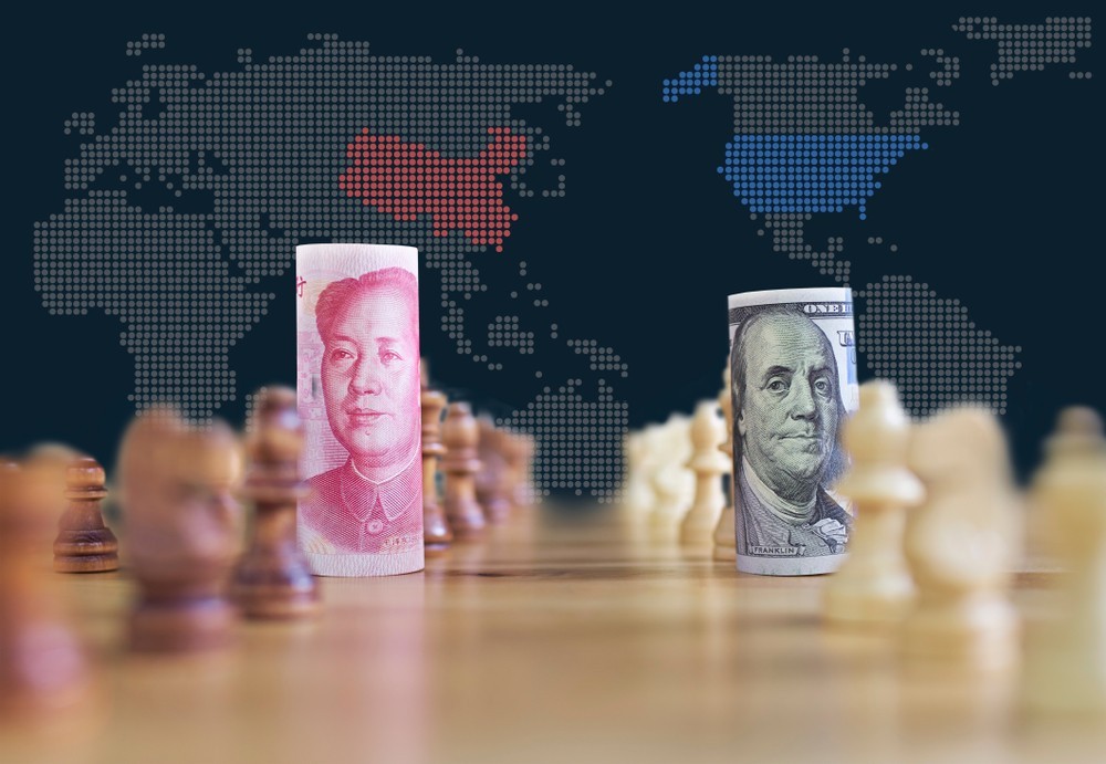 Wibest – Chinese yuan and US dollar bill rolled up and placed on a chess board and behind it is the map of the US and China.