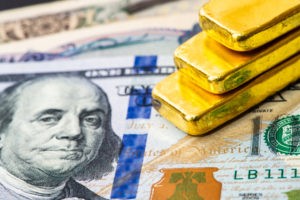 Wibest – Spot gold prices: Gold bars stacked up on top of US dollar bills.