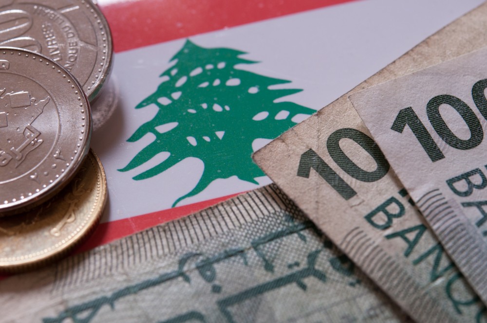 Wibest – Lebanese: The Lebanese pound coins and bills over Lebanon's flag.