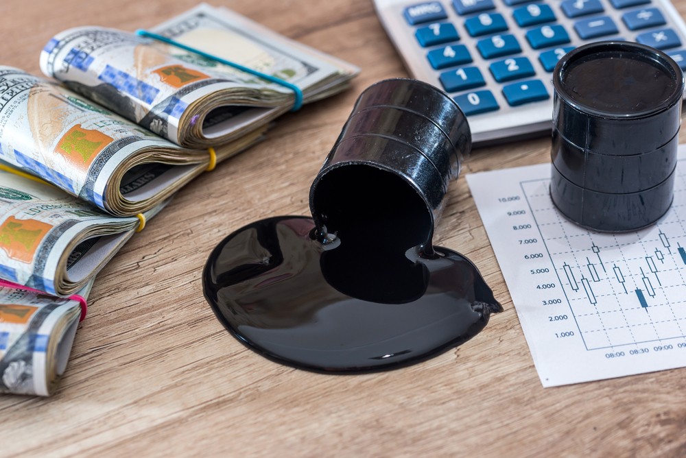 Wibest – Petroleum Crude: Crude oil barrel spilling crude on a desk with US dollar bills and a calculator.