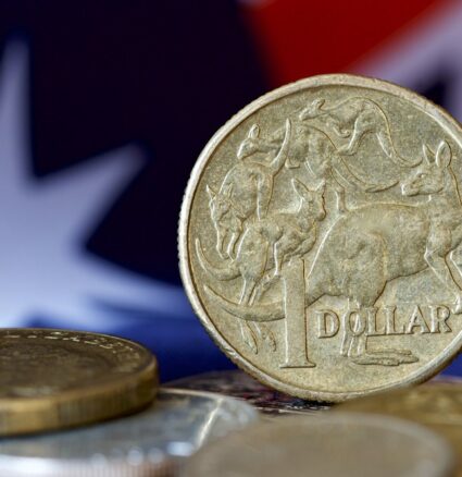 Wibest – Australian Money: Australian dollar (AUD) coins and the Australian flag behind.