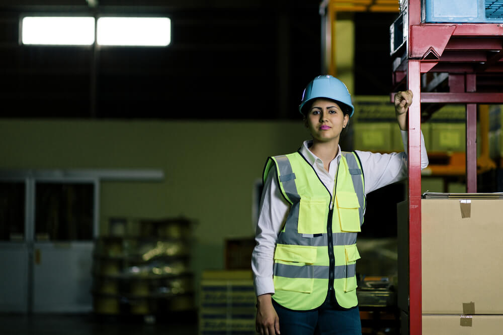  female warehouse worker with helmet and safety vest.