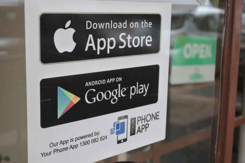 App Store and Google Play stickers on a shop door.