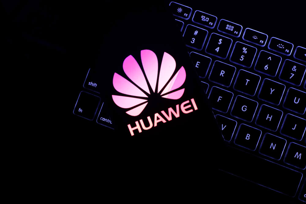 Computer keyboard and cell phone with the Huawei logo.