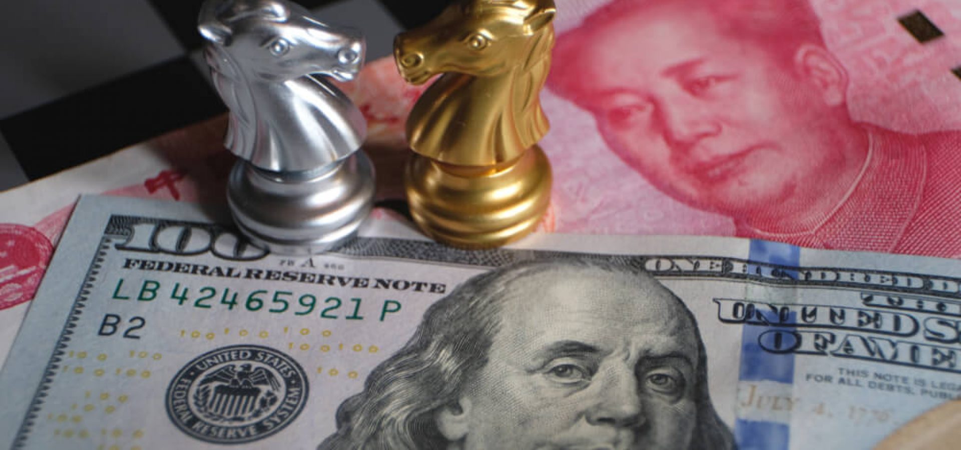Wibest Broker-Economic Development: silver and gold knight chess pieces on top of dollar and yuan banknotes