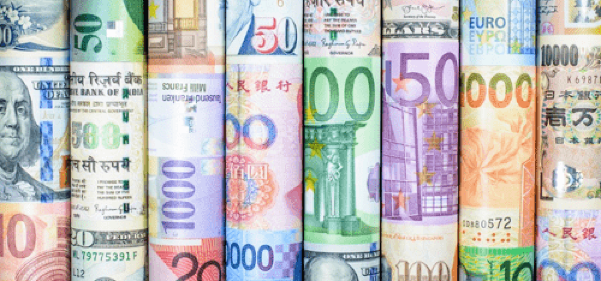 currency market concept; different currencies rolled – WibestBroker