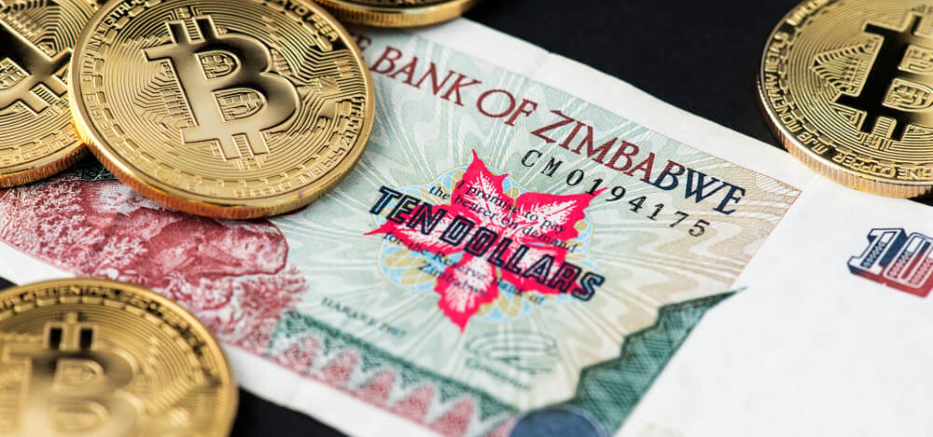 Digital Coins: Bitcoin on Zimbabwe hyperinflation banknote close up.