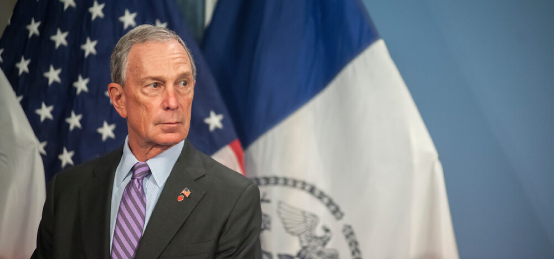 Mike Bloomberg photo with flags background.
