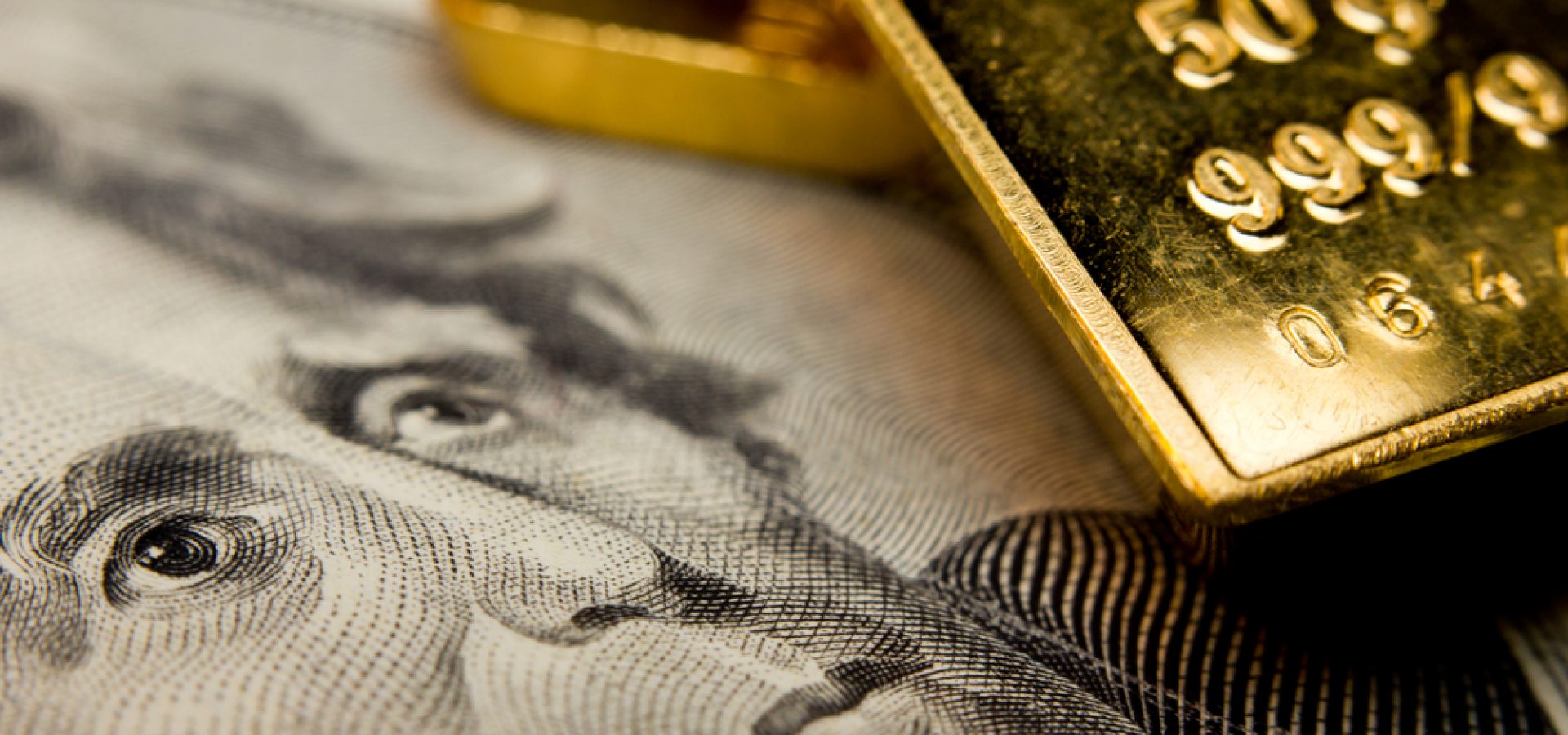 Wibest – Spot gold prices: A close up shot of a gold bar over a US dollar bill.
