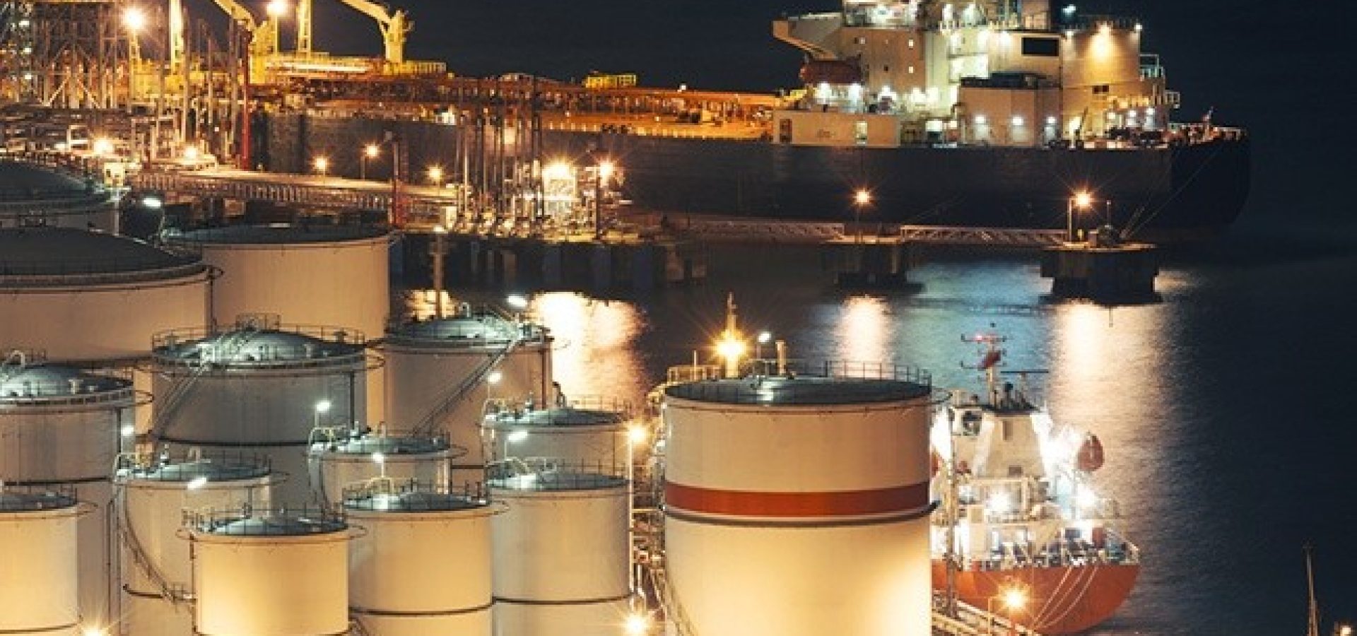Wibest – Oil: An aerial shot of oil inventories and a ship behind on nighttime.