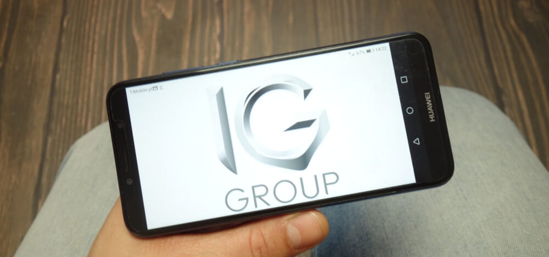 IG Group company logo displayed on Huawei smartphone.
