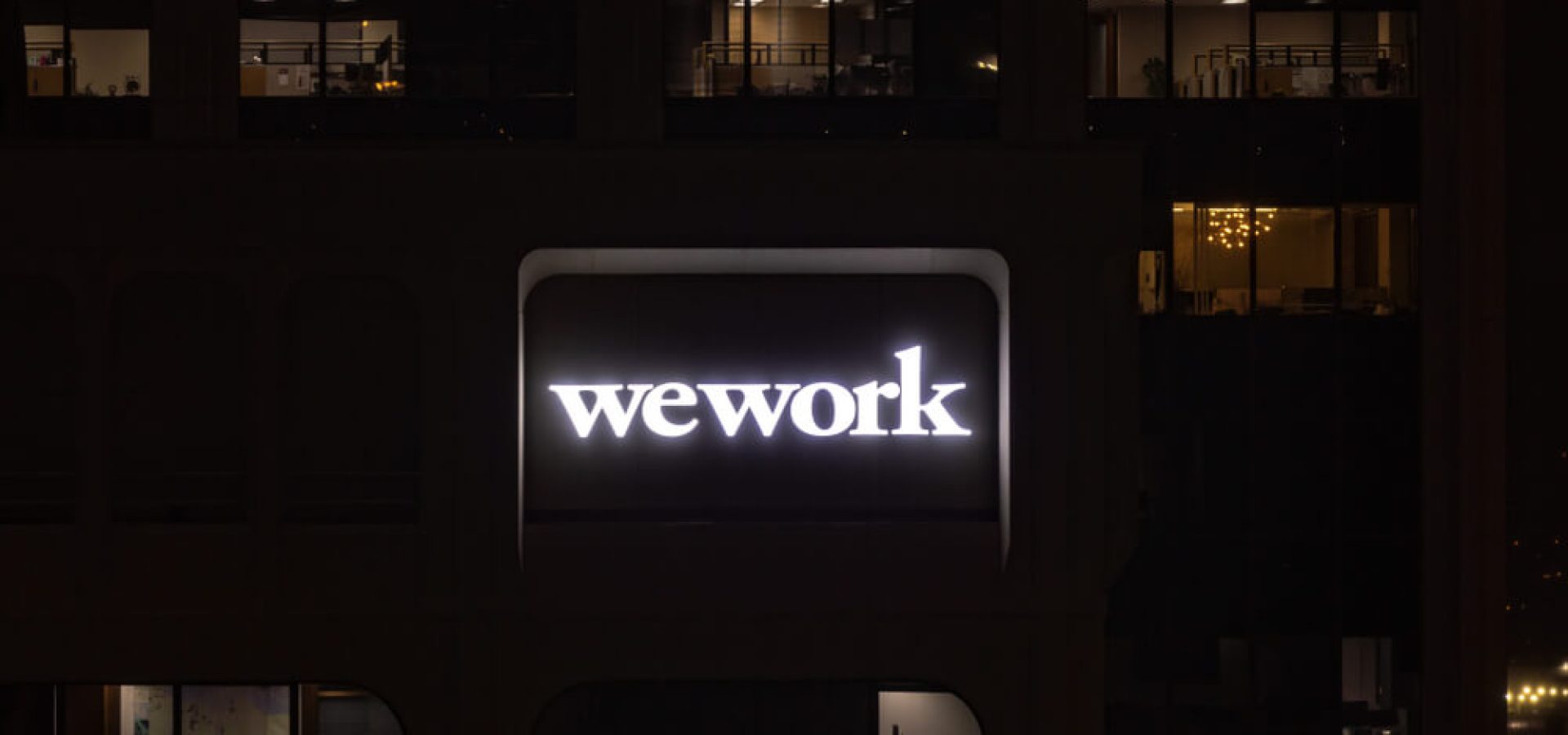 Legere: A night shot of a logo of WeWork company on a side of a building.