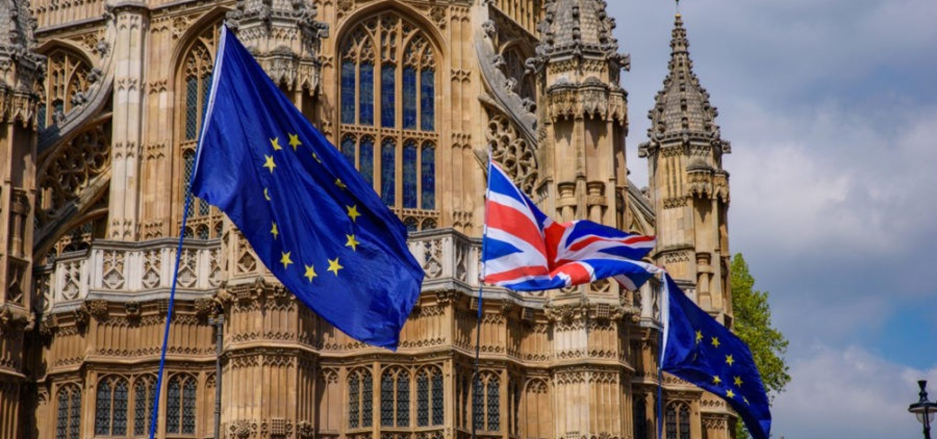 Wibest – UK Currency: The UK and EU flags in front of the UK parliament.
