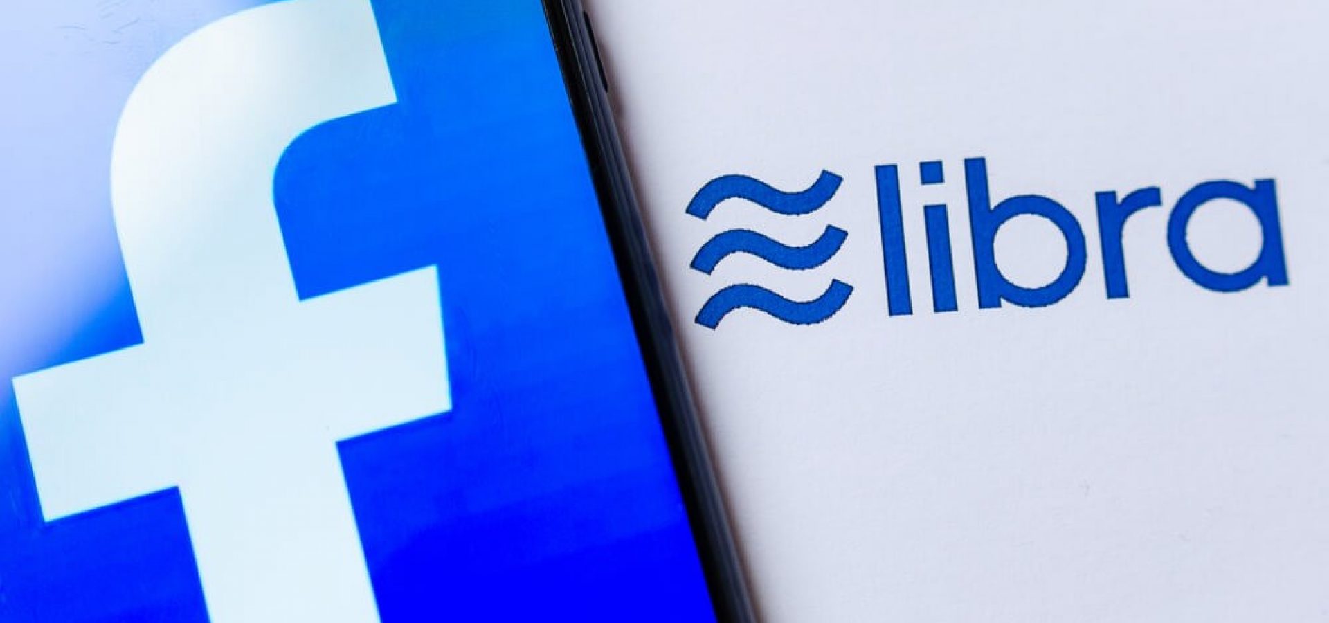 Wibest – Facebook Libra: Photo of the Facebook logo on the smartphone screen and the brochure with Libra logo.