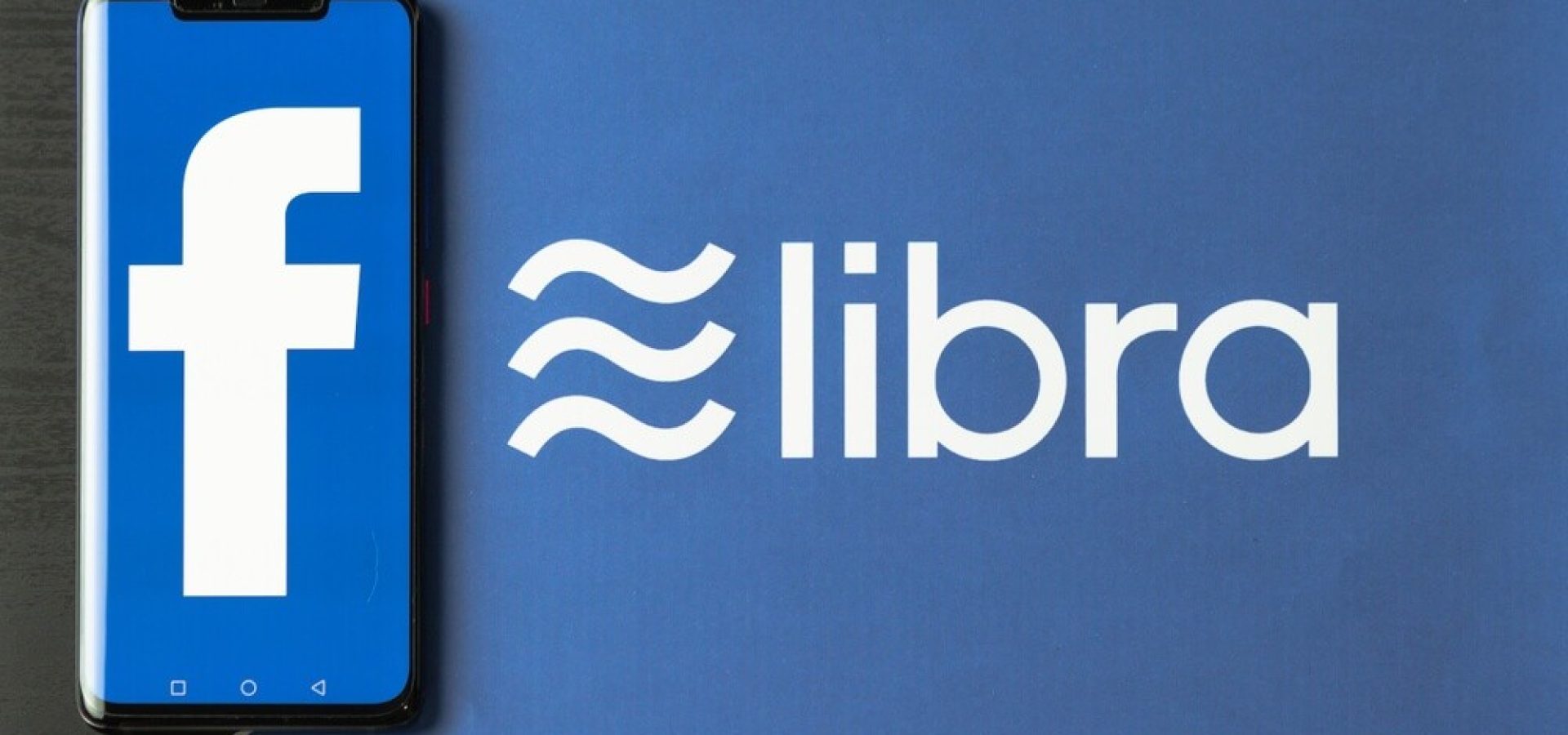 Wibets - FB: Phone with Facebook logo on screen is placed on paper with Libra logo.