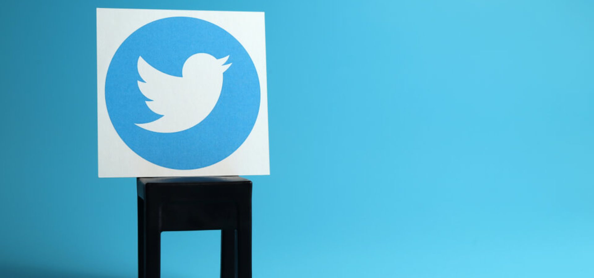 Twitter: Twitter logo on a black chair, light blue background.