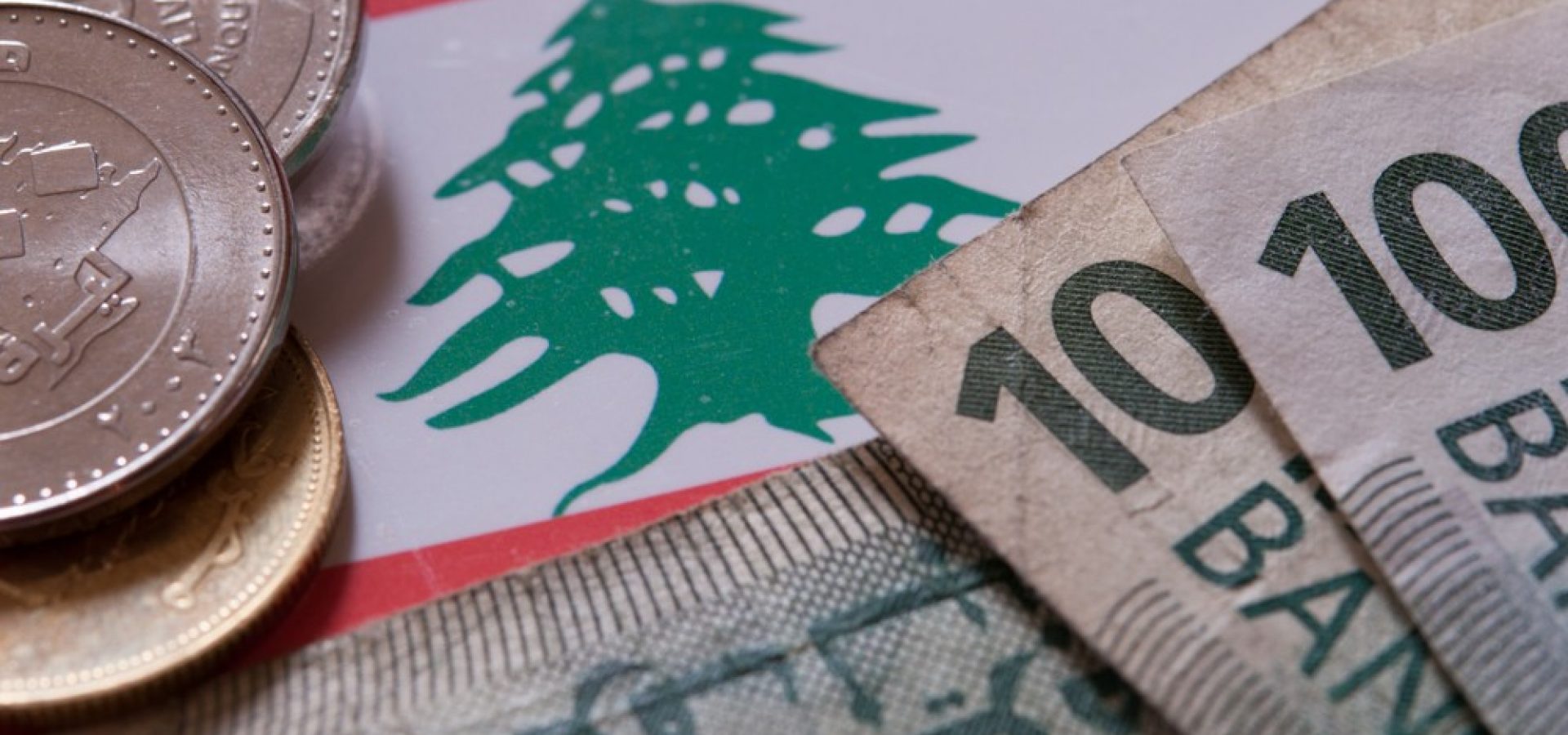 Wibest – Lebanese: The Lebanese pound coins and bills over Lebanon's flag.