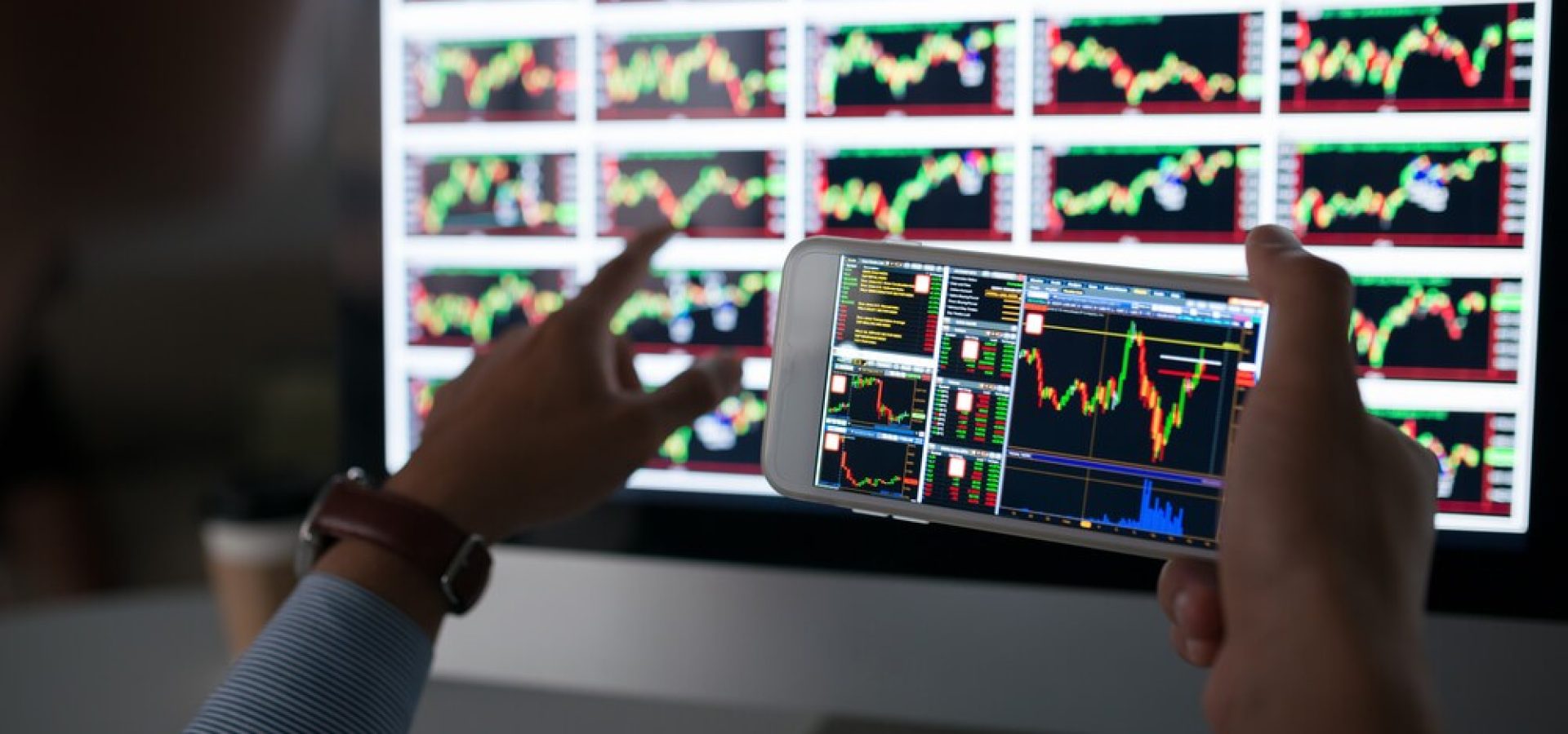 Trader: Hands of trader holding smartphone with stock market app
