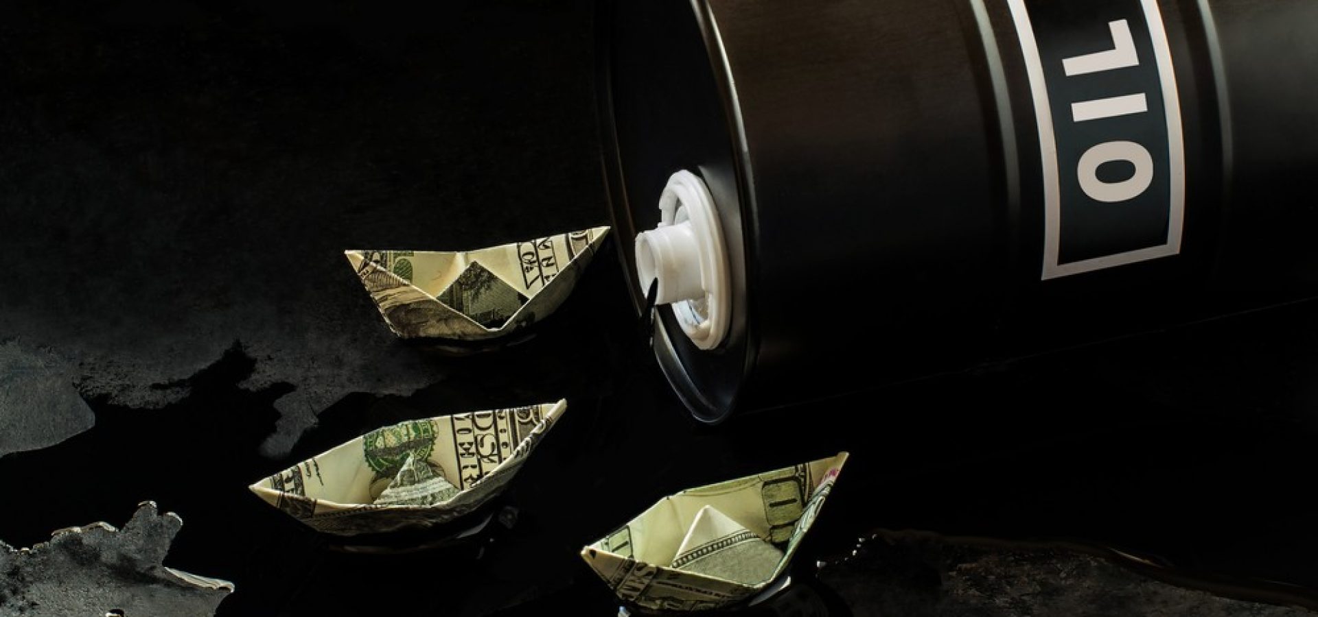 Wibest – Oil and petroleum: Oil barrel spilling crude and US dollar bills folded like boats floating.