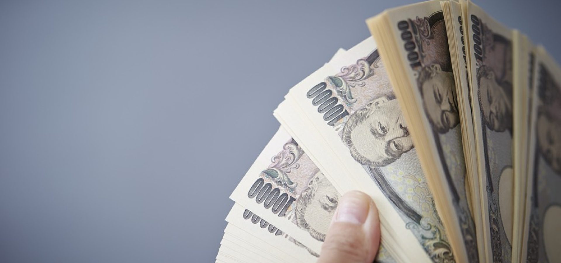Wibest – Yen exchange rate: Hands holding Japanese yen bills.