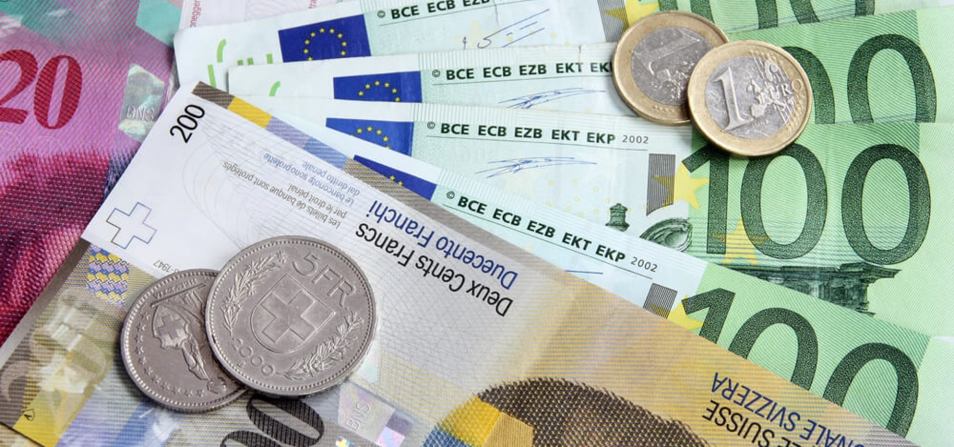 usd/chf – EUR to CHF: Euro and Swiss Franc coins and bills.