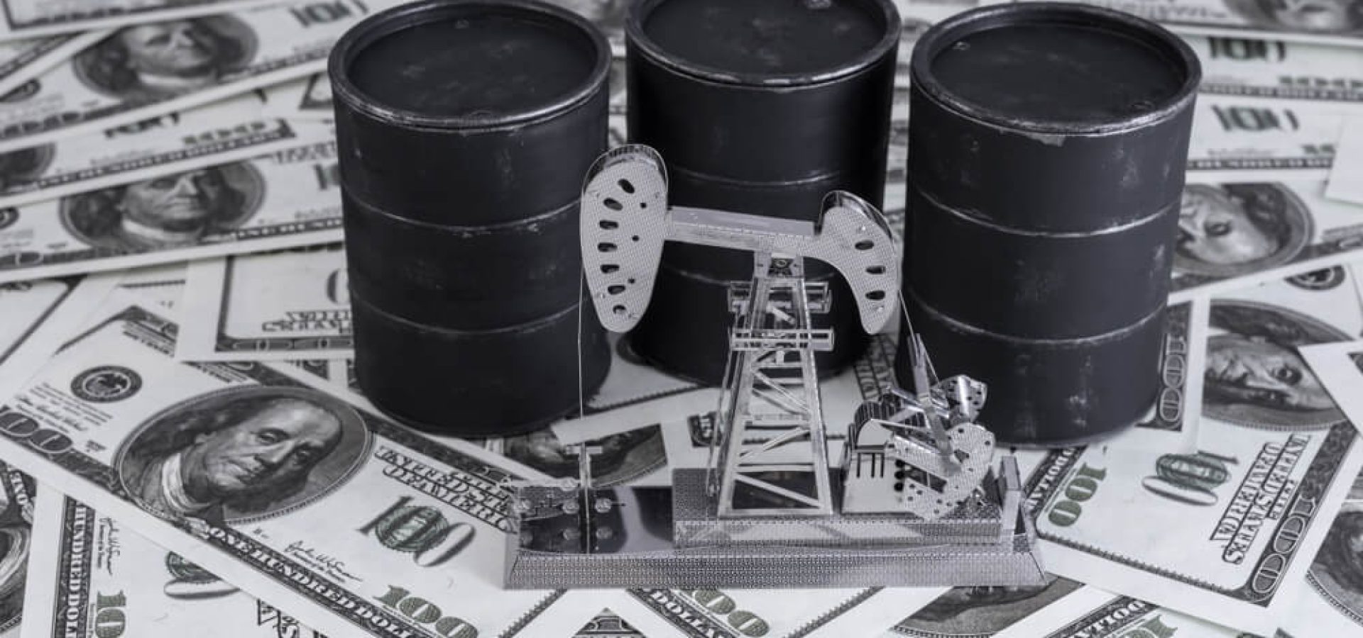 miniature oil barrels on top of dollar bills